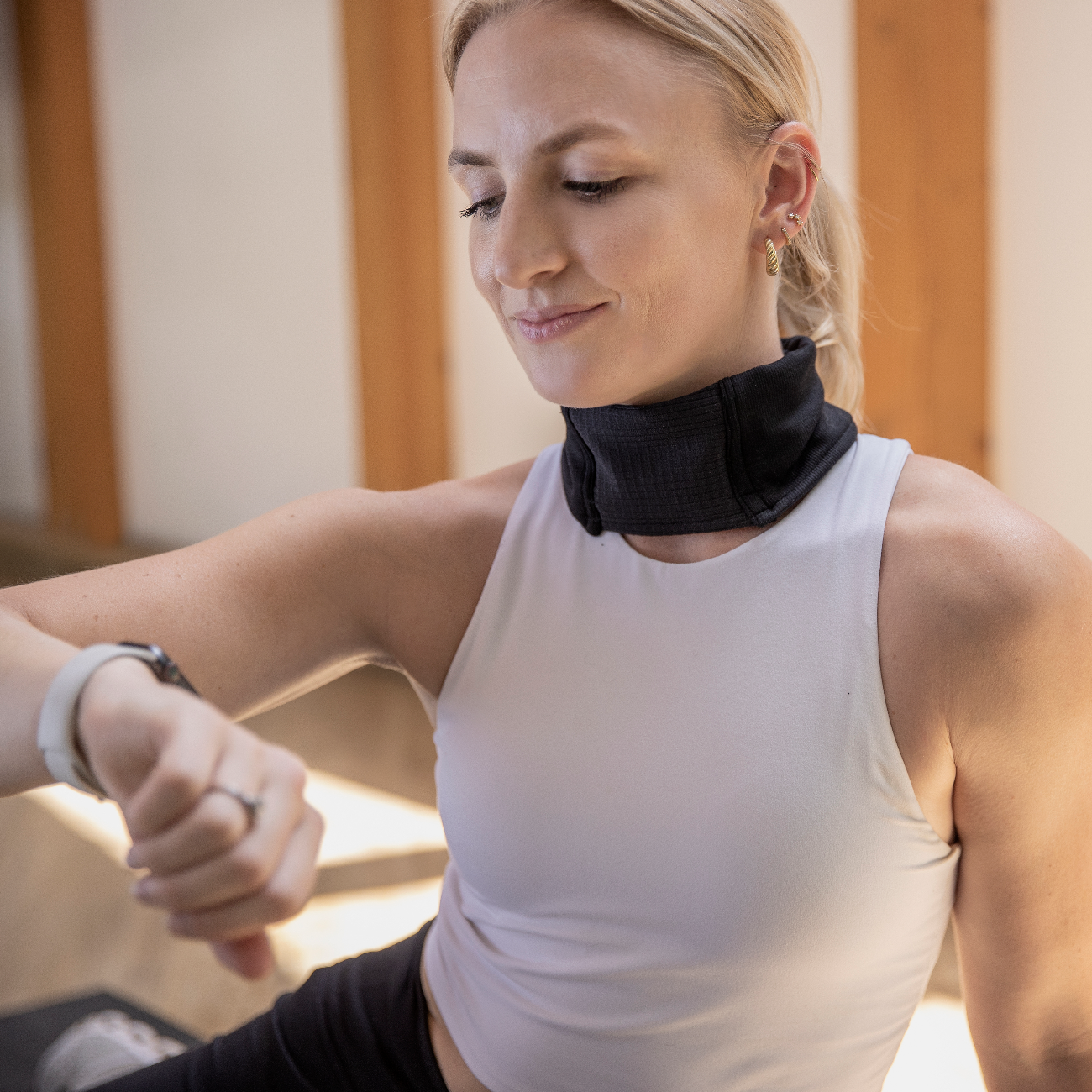 Woman in a yoga clothing adjusting the WaveStopper Thyroid Gaiter.