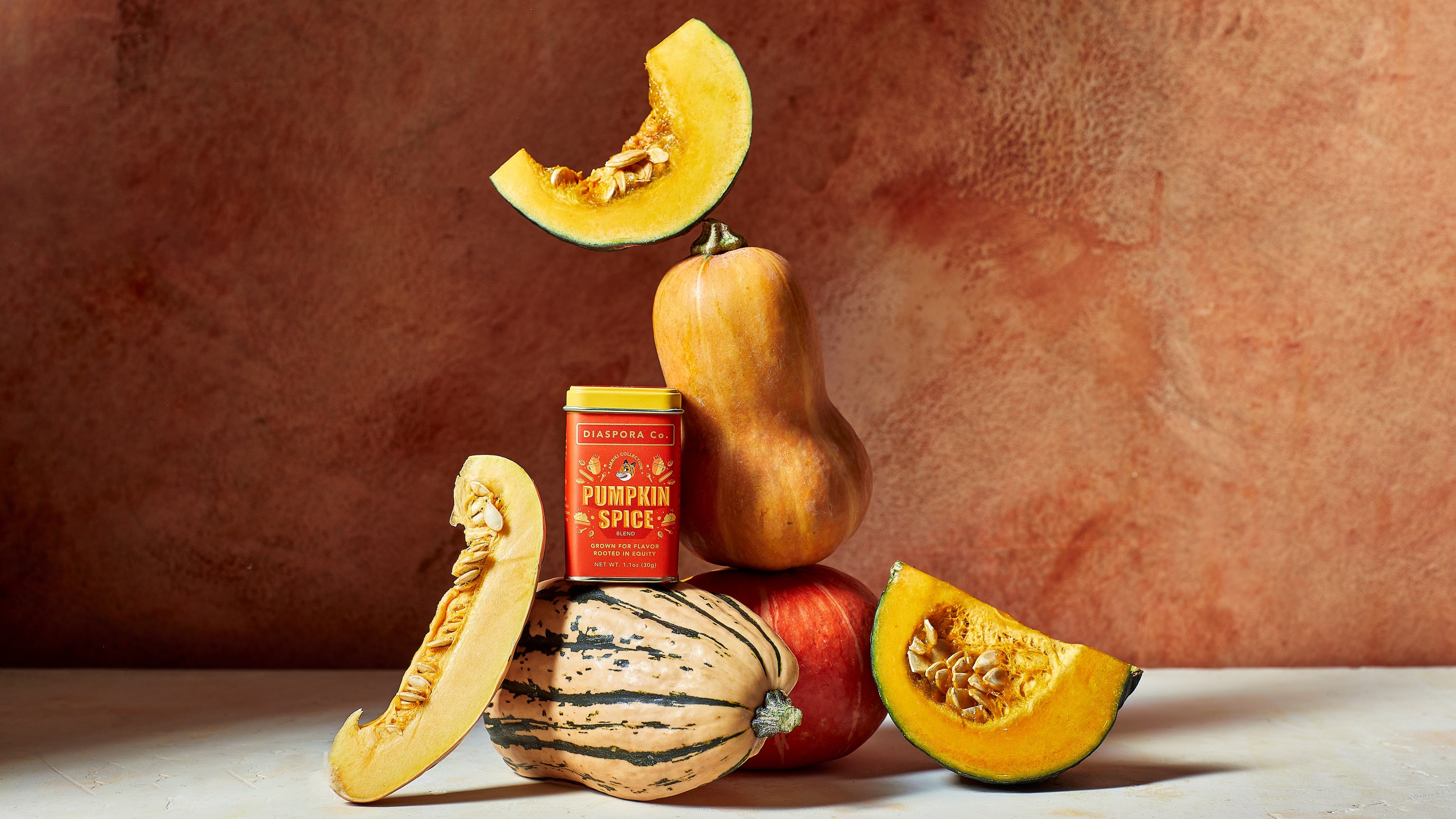 Orange can of Diaspora Co. Pumpkin Spice sitting on top of different pumpkins and squash.