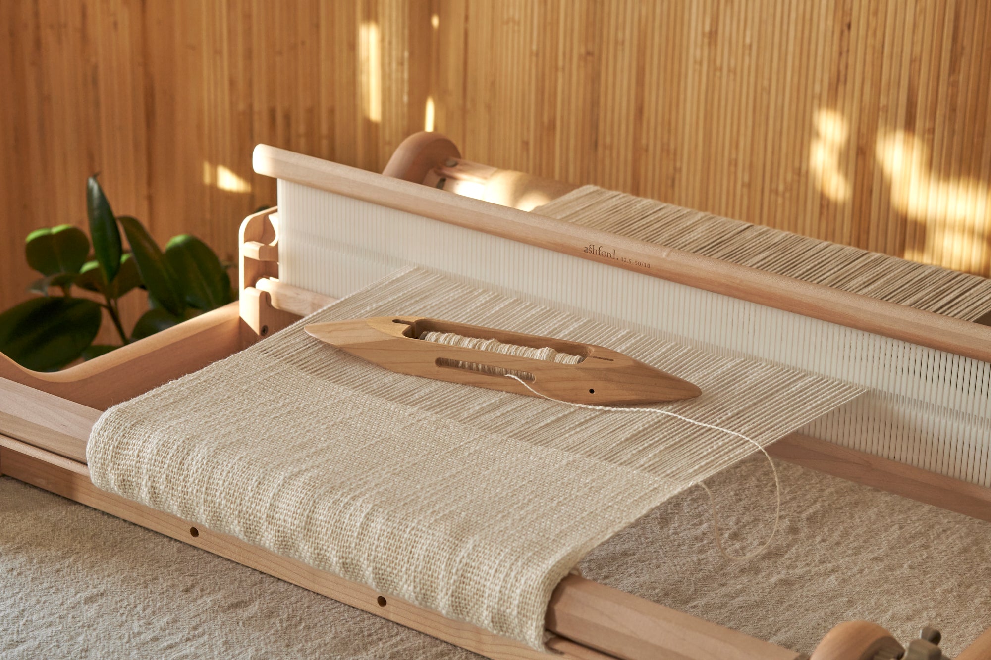 A wooden weaving tool setup against a wooden background.