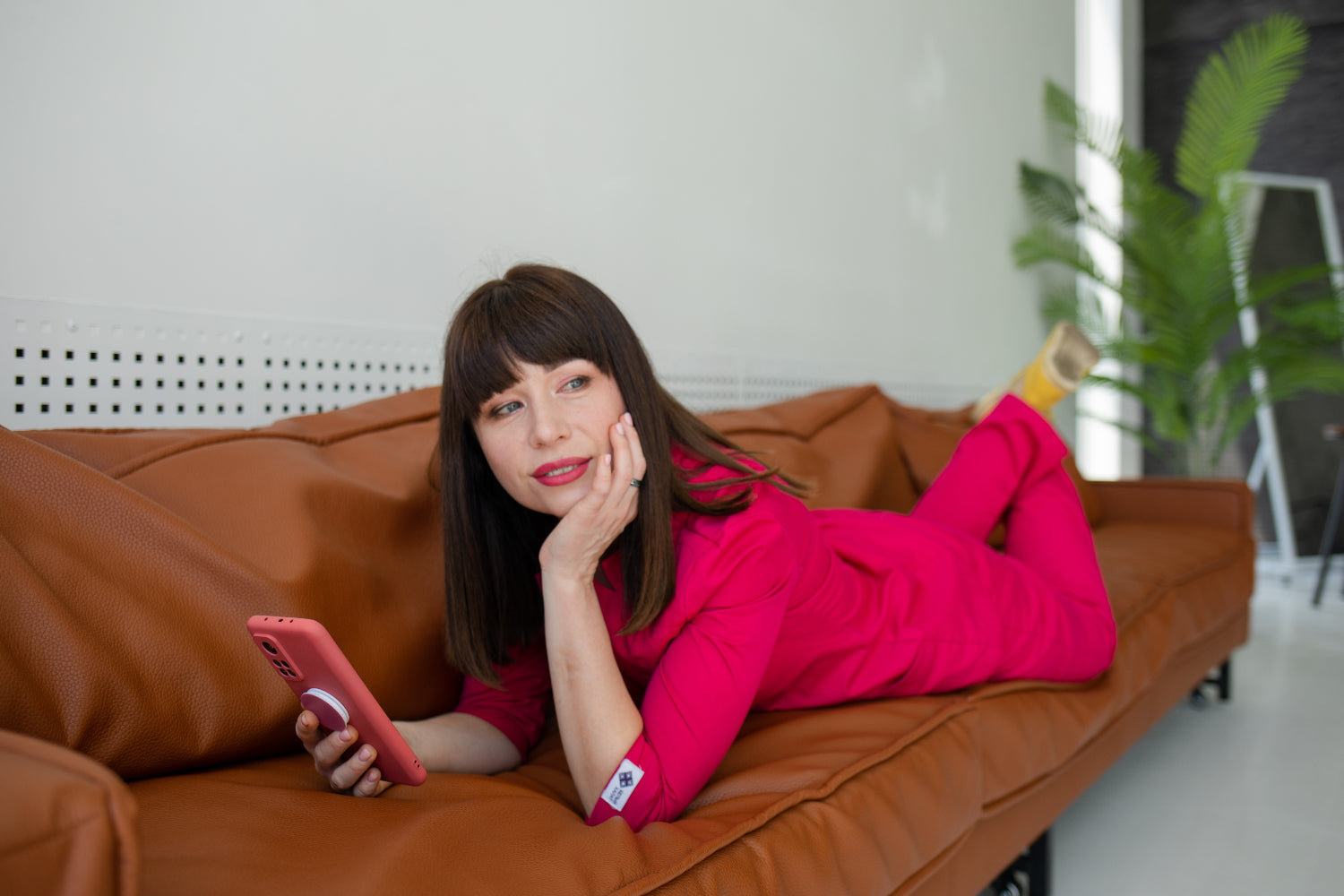 A woman on a sofa with a TikTok video playing on her phone.