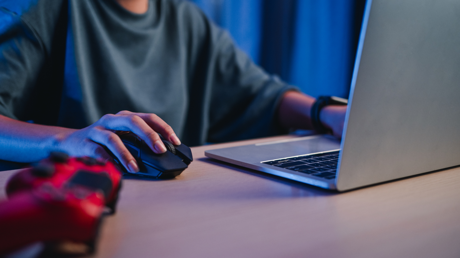 Een persoon op een laptop met een muis en gaming controller