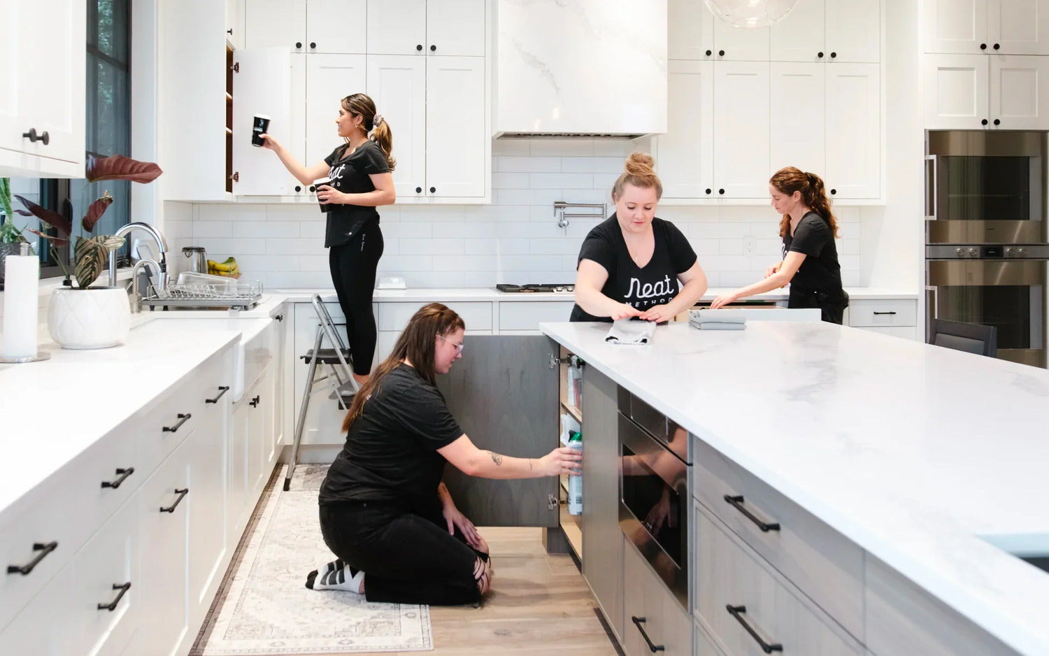 Vier vrouwen die een witte keuken opruimen
