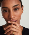 Woman wearing Small Hoops, hand on chin, showcasing light, everyday gold earrings perfect for all-day wear.