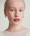 Woman with blonde hair wearing Puffy Charlotte Hoops earrings from the Charlotte Collection, designed for making a bold statement.