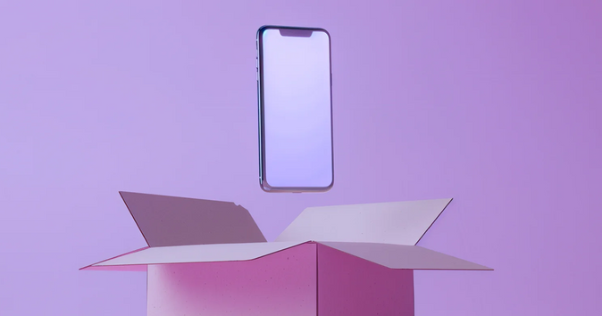 Das Bild zeigt ein Smartphone, das über einem geöffneten Karton schwebt.