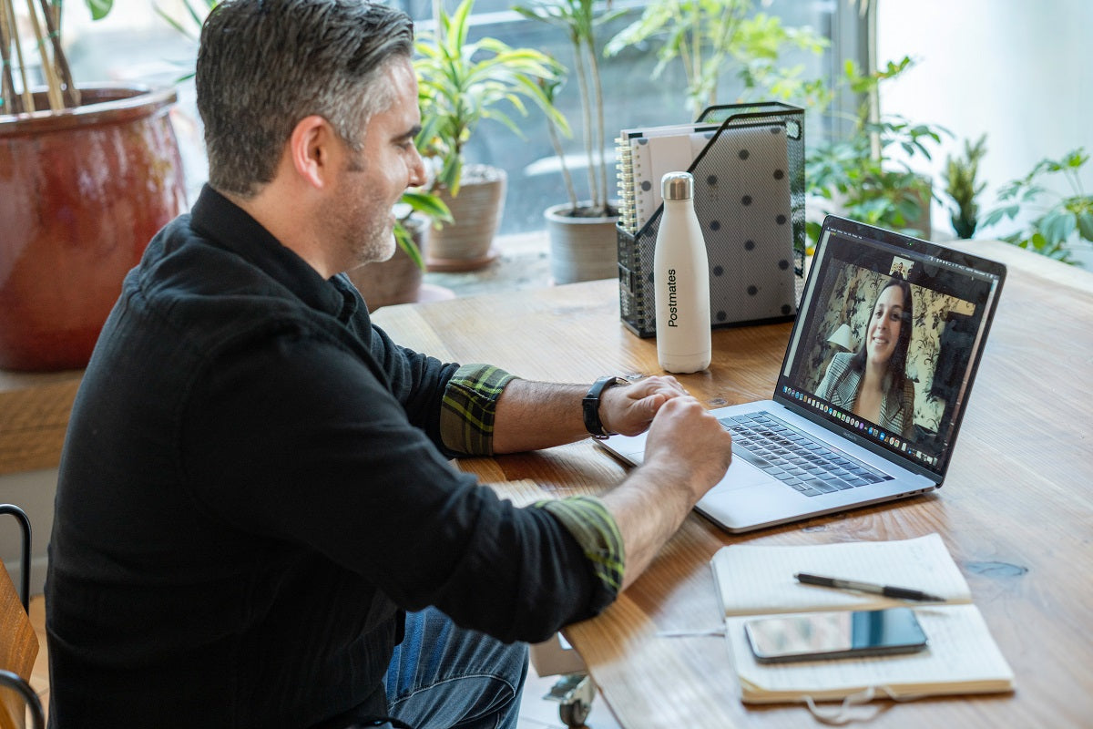 Ein Mann sitzt vor einem Laptop und telefoniert online.